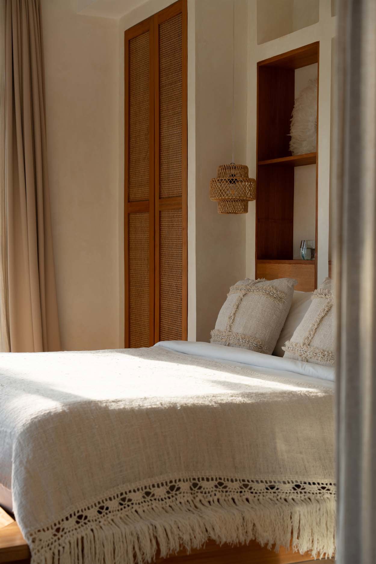 Kayu Living Gypsy Bed Throw in natural cotton with delicate crochet lace trim and fringe draped over a bohemian bed.