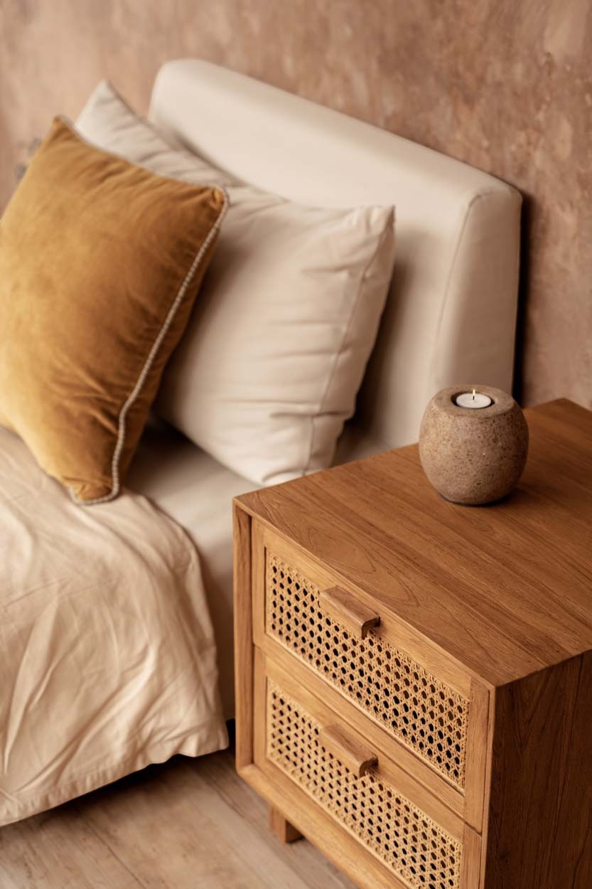 Kayu Living Harmony nightstand in solid teak wood with two handwoven rattan drawers in a cozy bedroom setting.