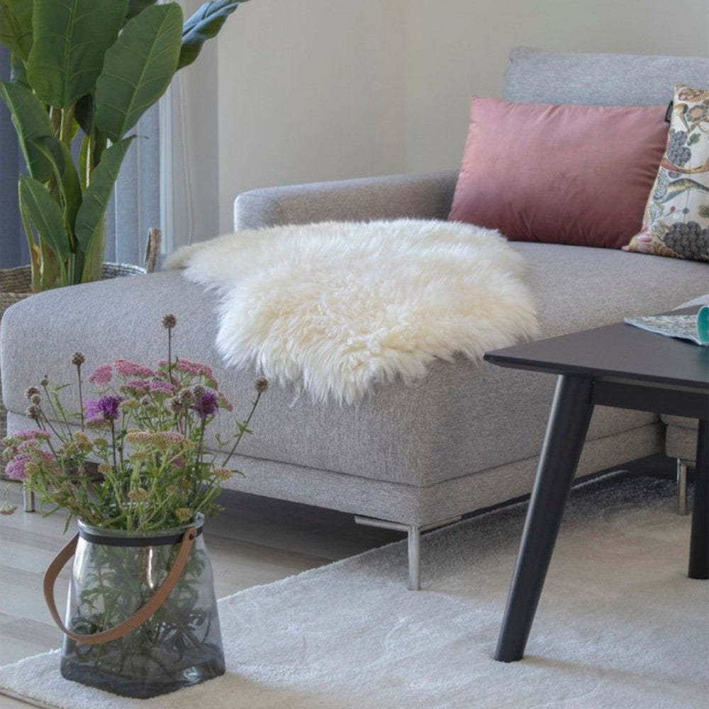 Kayu Living ivory lambskin throw with 5cm pile draped over a grey sofa in a cozy living room setting
