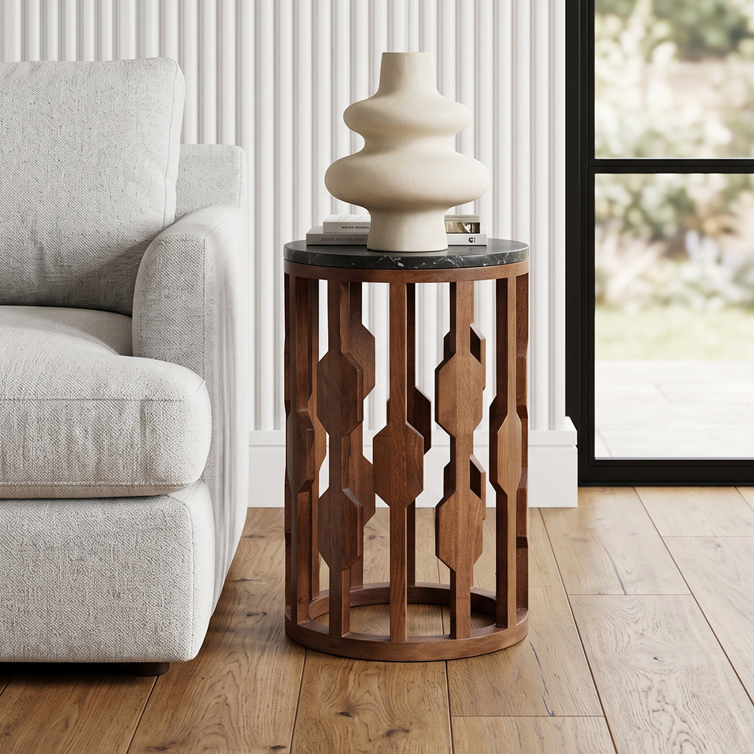 Kayu Living Lampung round side table with black marble top and intricate dark mango wood base next to a sofa
