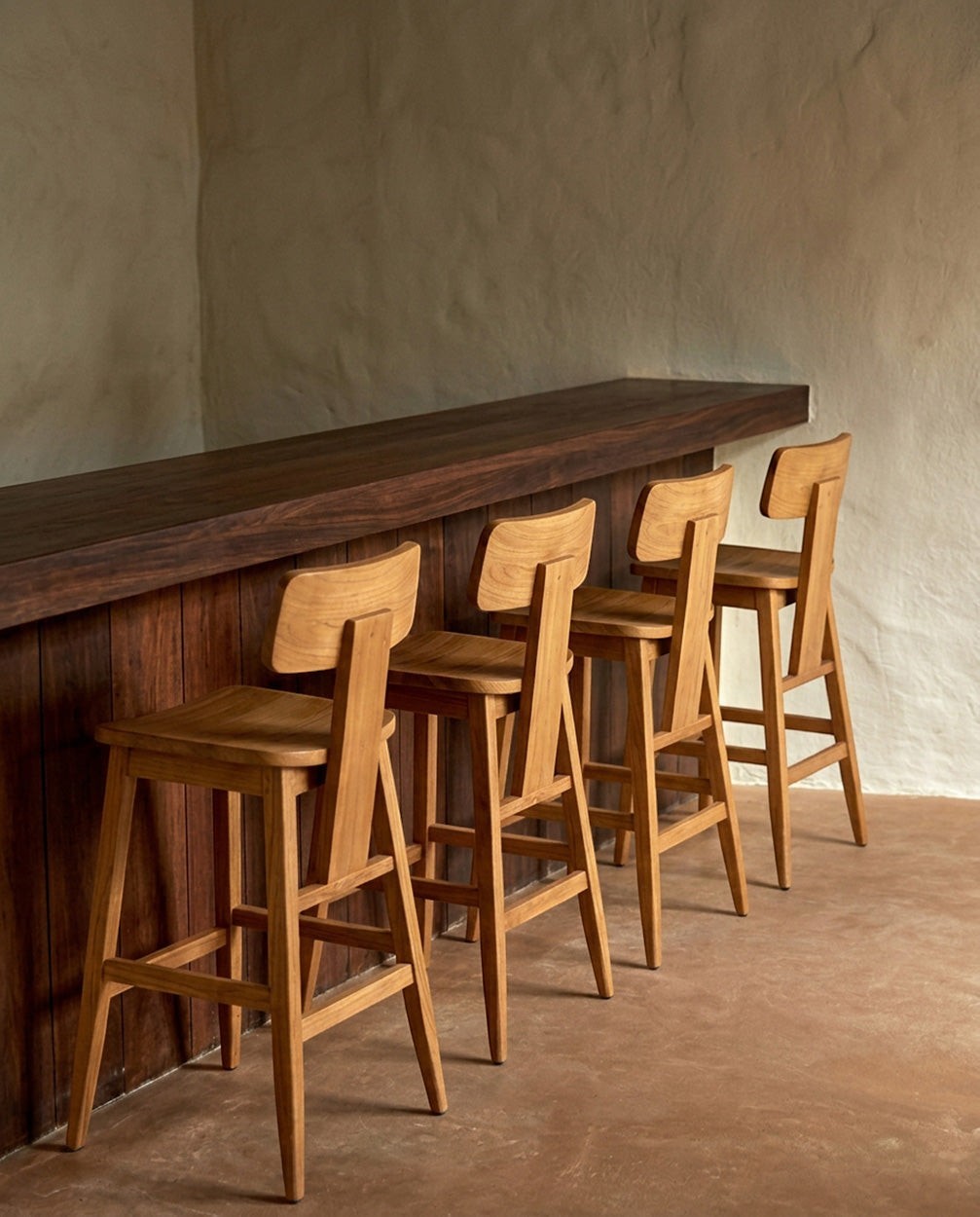 Kayu Living LovYa teak barstools with modern minimalist design arranged at a dark wood kitchen counter.