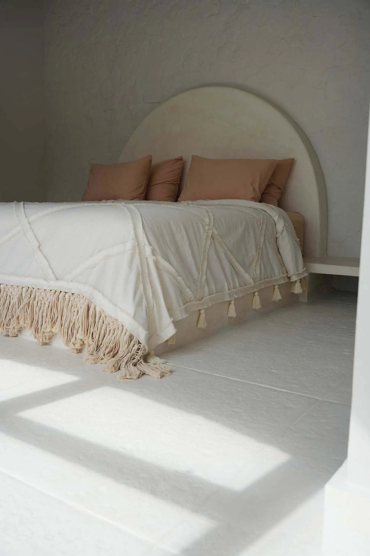 Kayu Living natural Berber cotton bed throw with textured plaid pattern and decorative tassels on a white bed