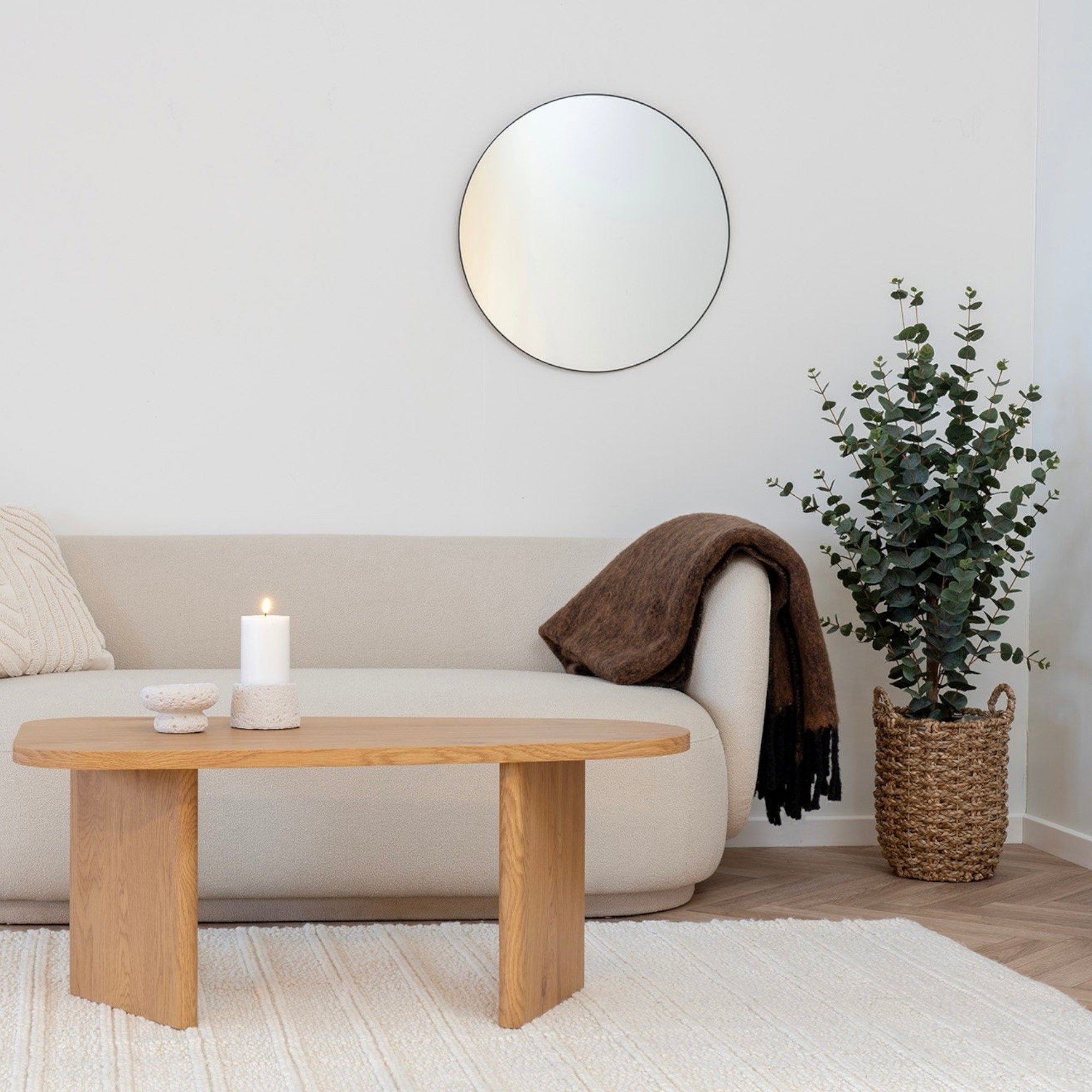 Kayu Living set of three natural seagrass baskets in graduated sizes placed next to a sofa in a modern living room
