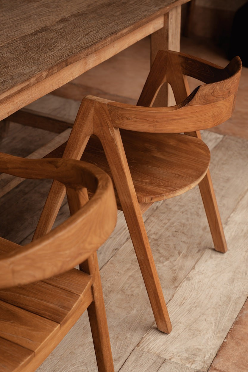 Kayu Living Nihi Sumba outdoor dining chair in natural teak with sculpted curves and crisp lines.