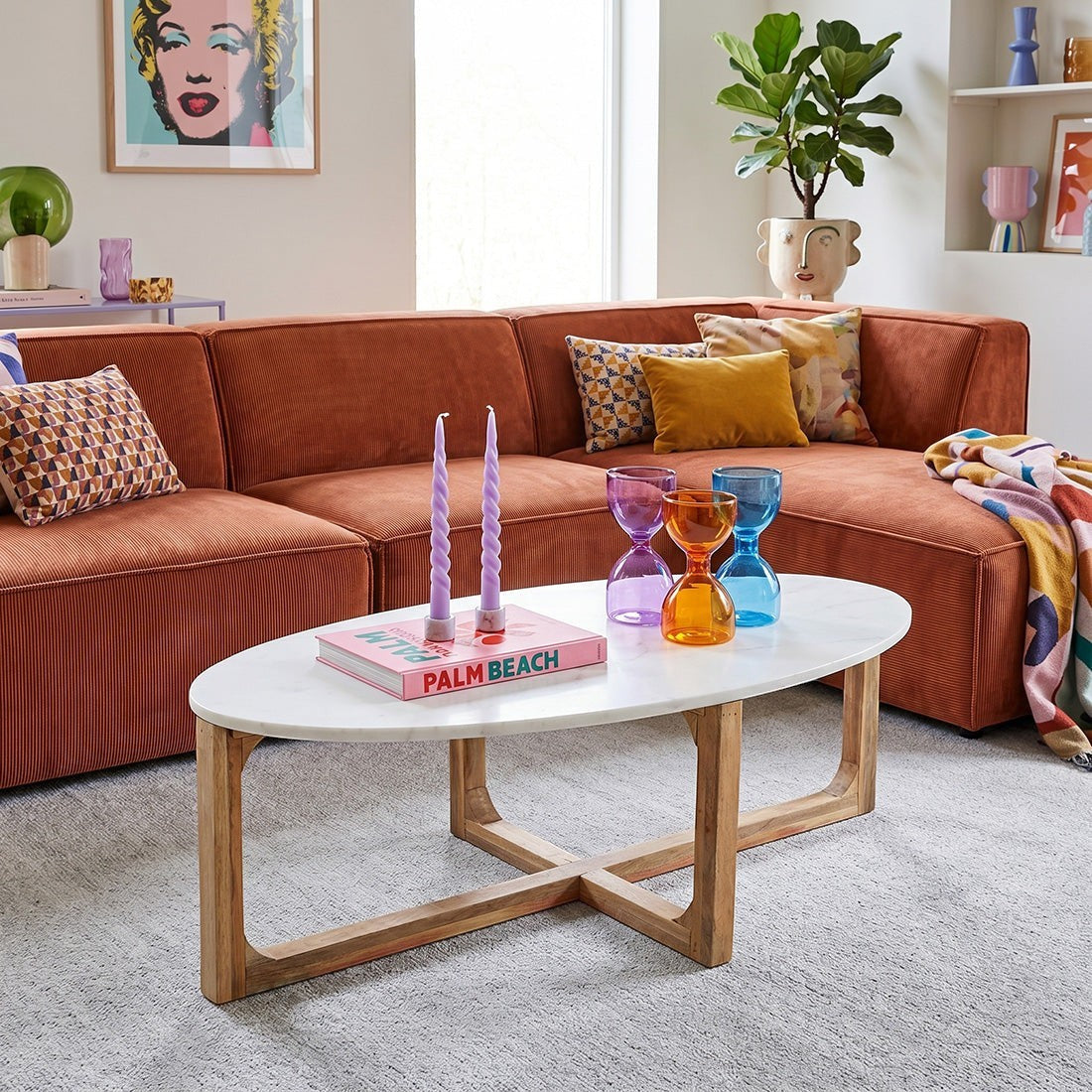 Kayu Living oval white marble coffee table with a natural mango wood base in a modern living room setting