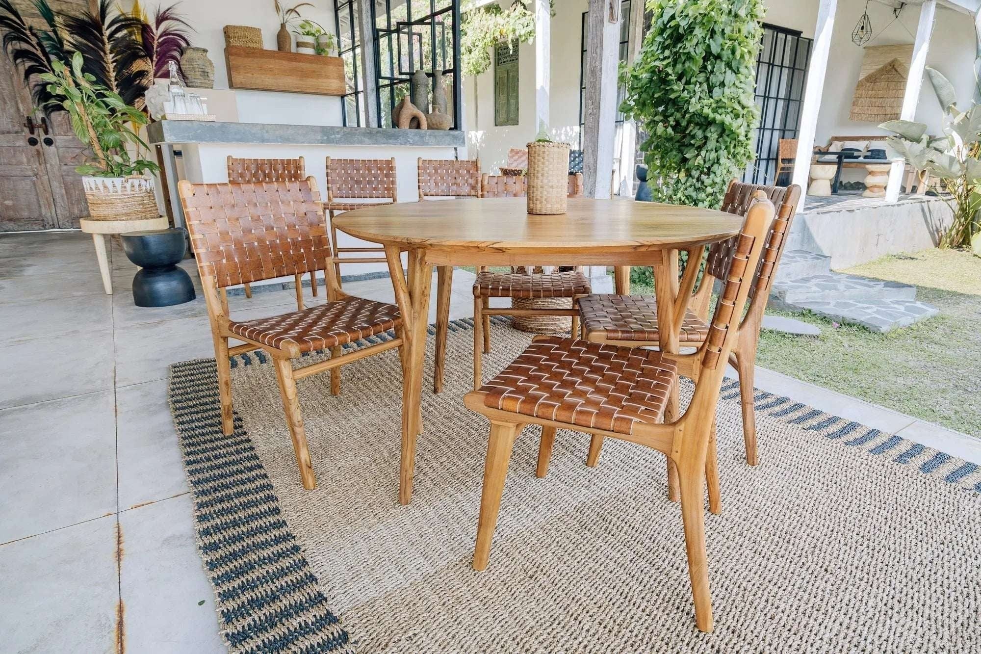 Kayu Living Pantai round teak dining table with woven leather chairs, 120 cm diameter, natural wood finish.