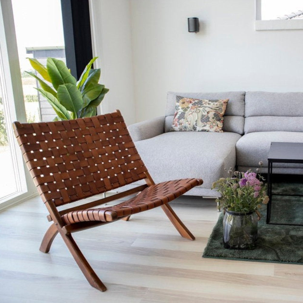 Kayu Living Perugia folding chair featuring woven brown leather seat and sturdy teak wood frame in a modern living room