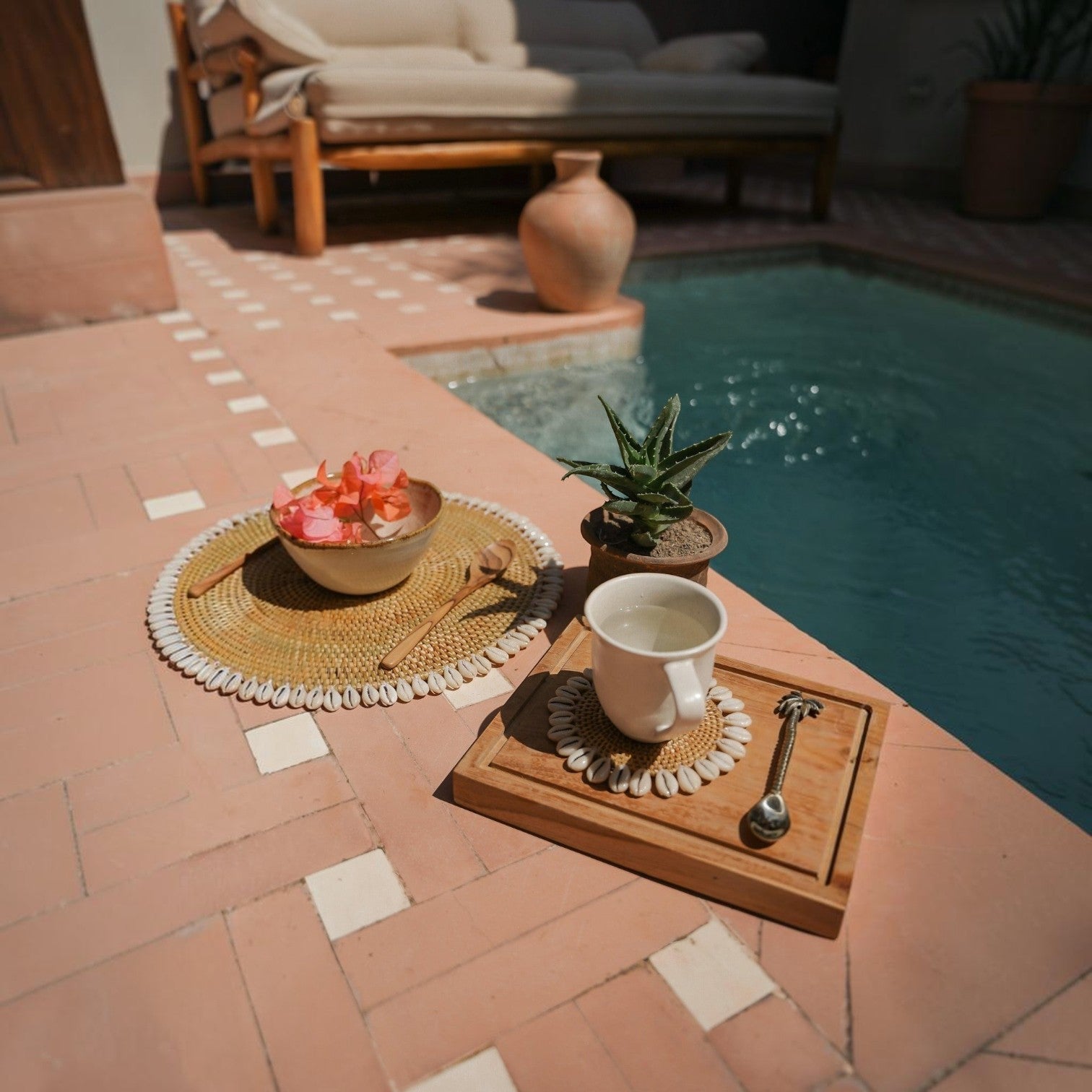 Kayu Living pineapple brass spoon on a wooden board next to a cup, styled in a bohemian poolside setting.