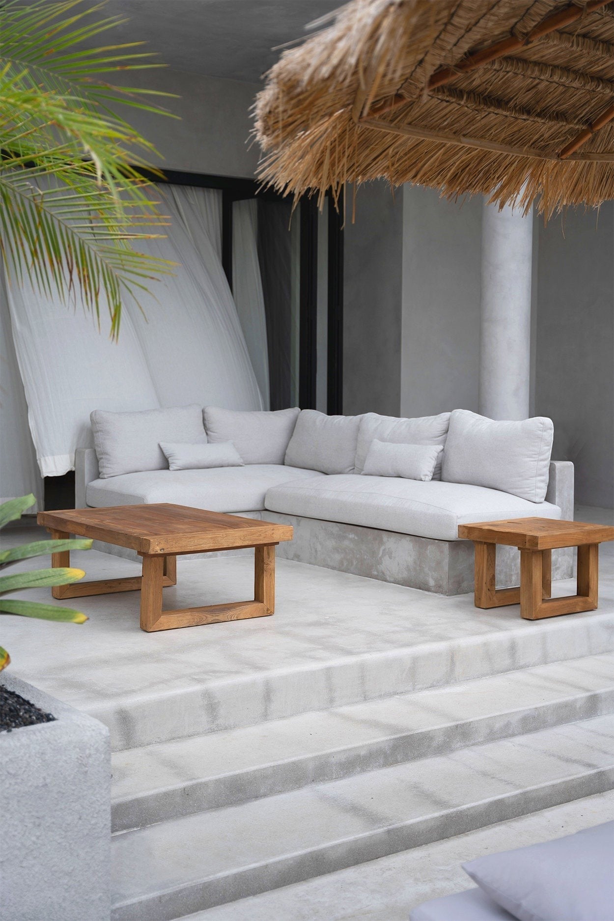 Kayu Living reclaimed teak coffee table with natural wood grain finish on a modern outdoor patio terrace.