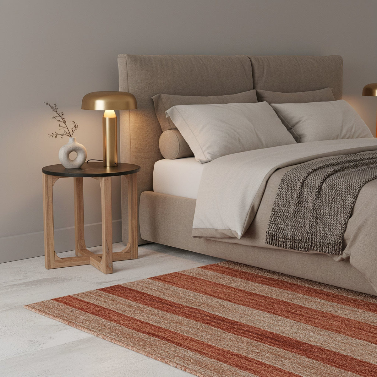 Kayu Living round black marble side table with white veining on a crossed mango wood base next to a beige bed