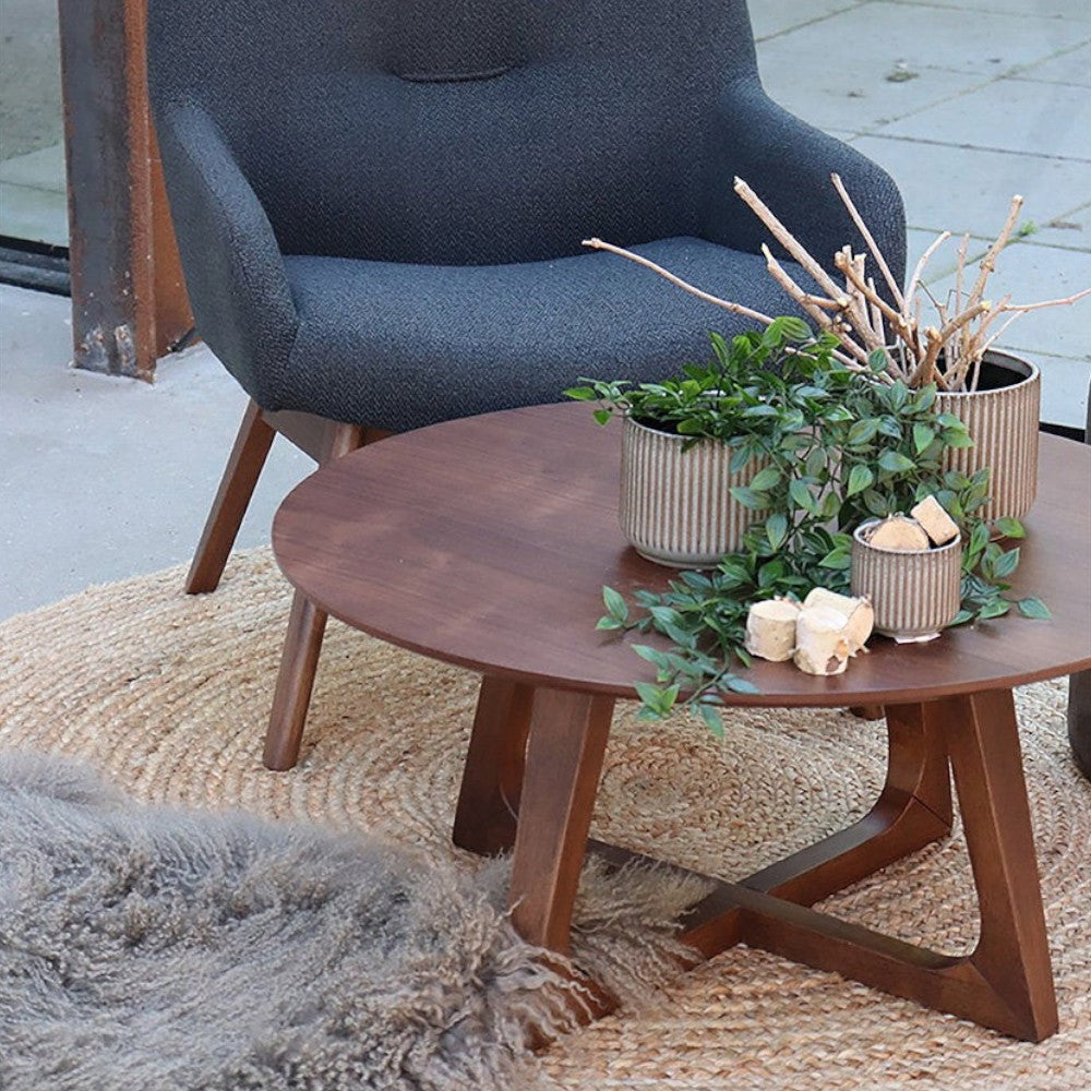 Kayu Living round braided natural jute rug under a dark wood coffee table and armchair in a modern living space