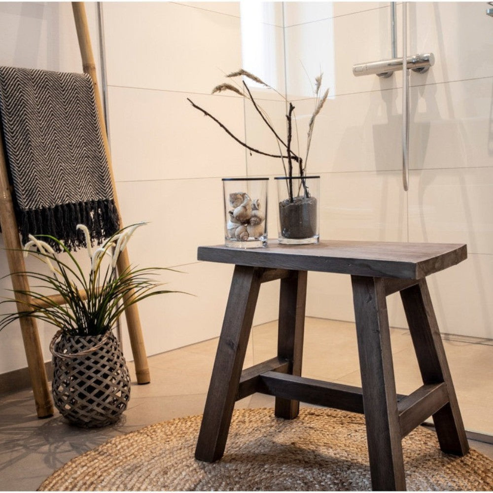 Kayu Living round handwoven natural jute rug with braided texture in a rustic bathroom setting