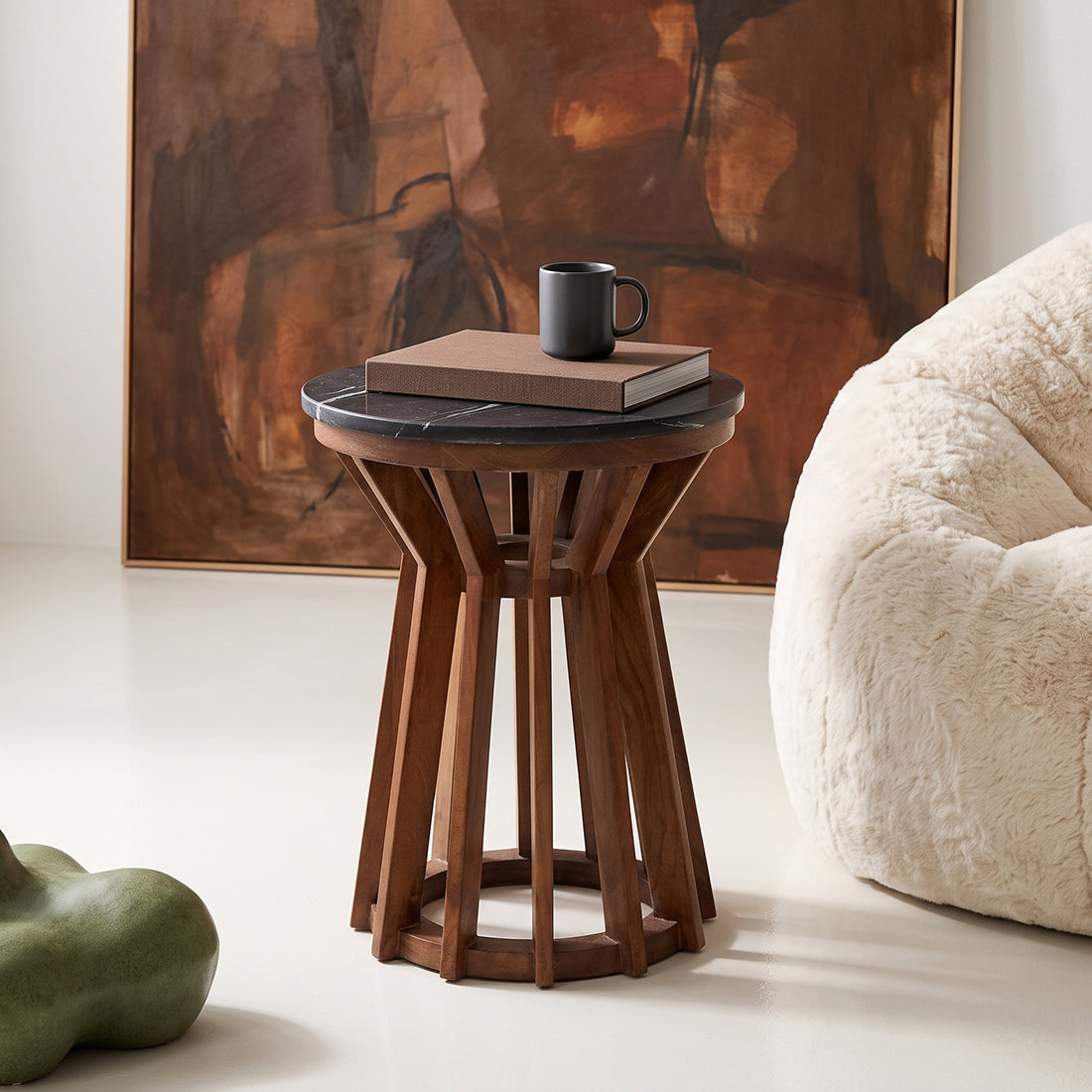 Kayu Living Sabah side table with a round black marble top and a dark mango-wood spoked base in a modern living room.