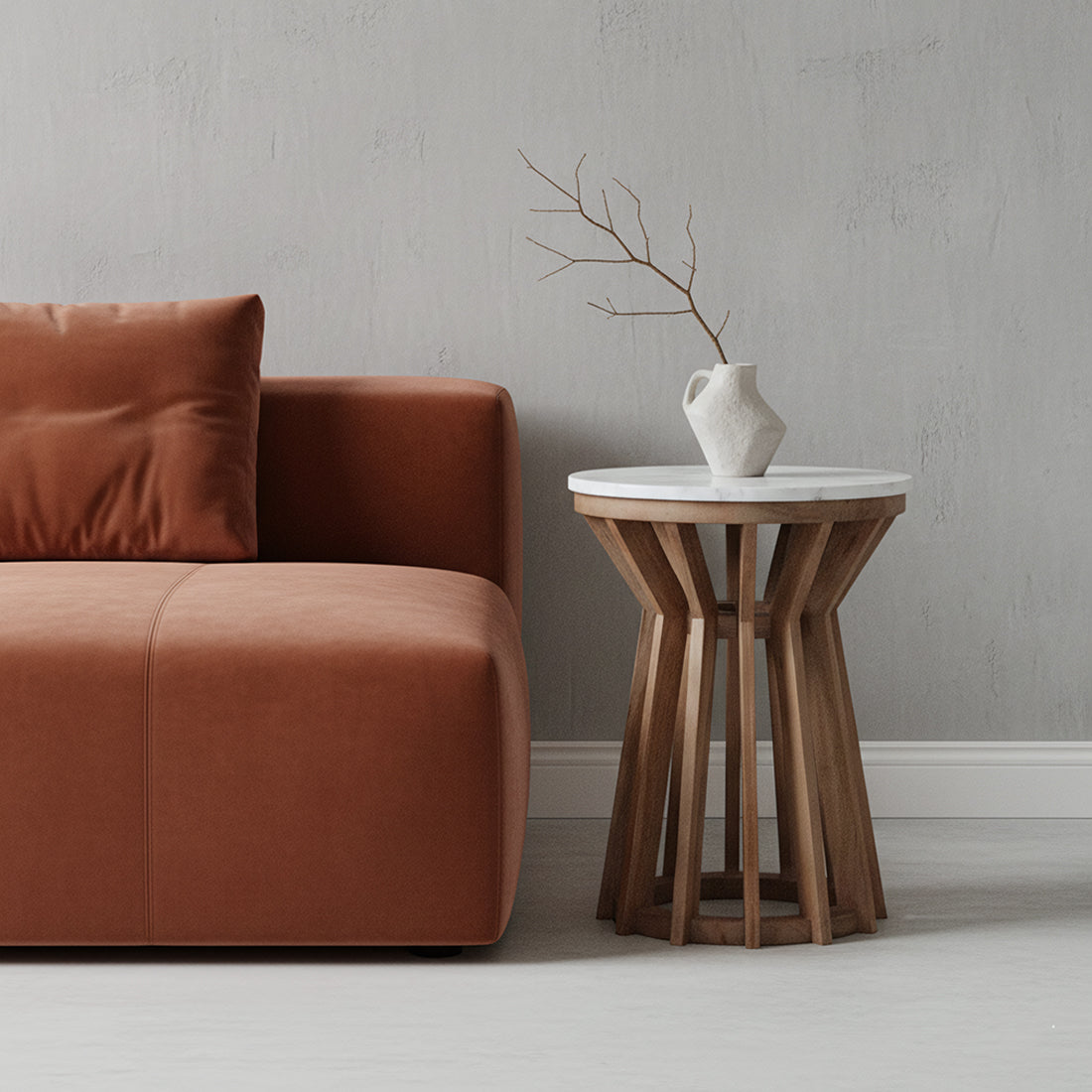 Kayu Living Sarawak round white marble side table with an open mango wood base next to a rust-coloured sofa