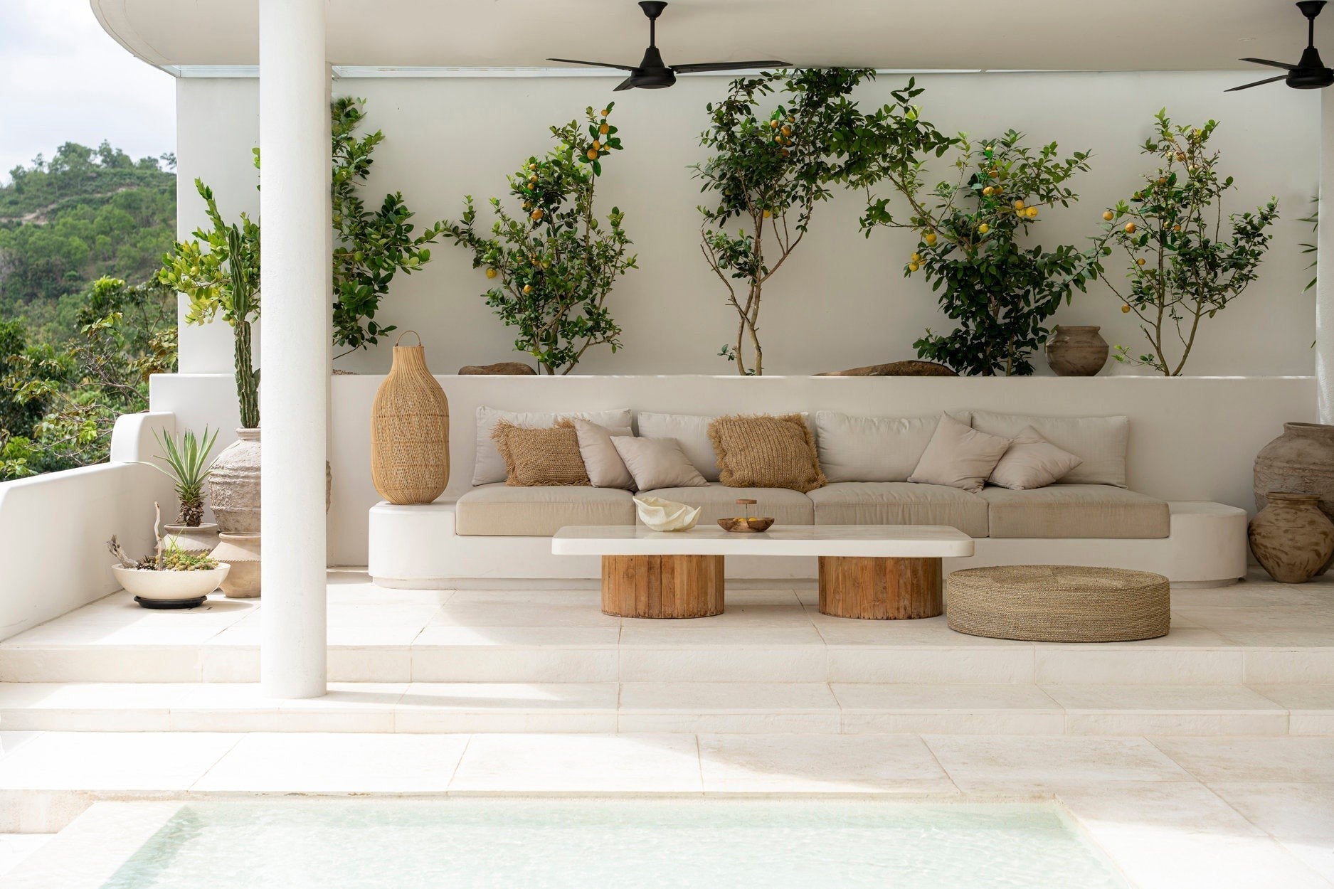 Kayu Living 100cm handcrafted seagrass pouf in a natural woven texture, placed on a modern outdoor patio by a pool.