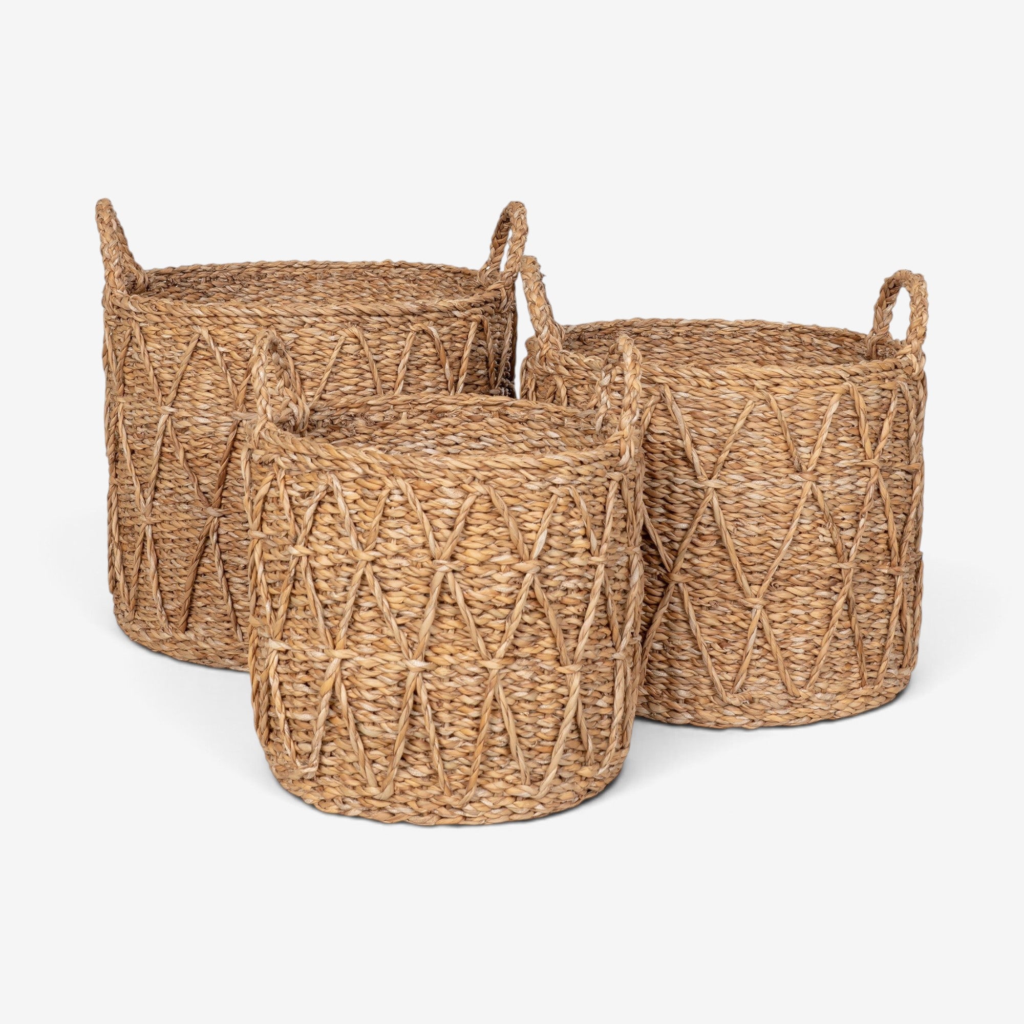 Kayu Living set of three handcrafted natural seagrass storage baskets with woven diamond patterns and side handles.