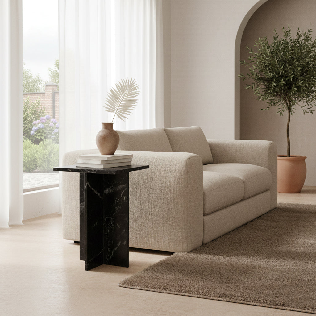 Kayu Living Shanghai black marble side table with white veining, featuring a crossed base next to a beige sofa.