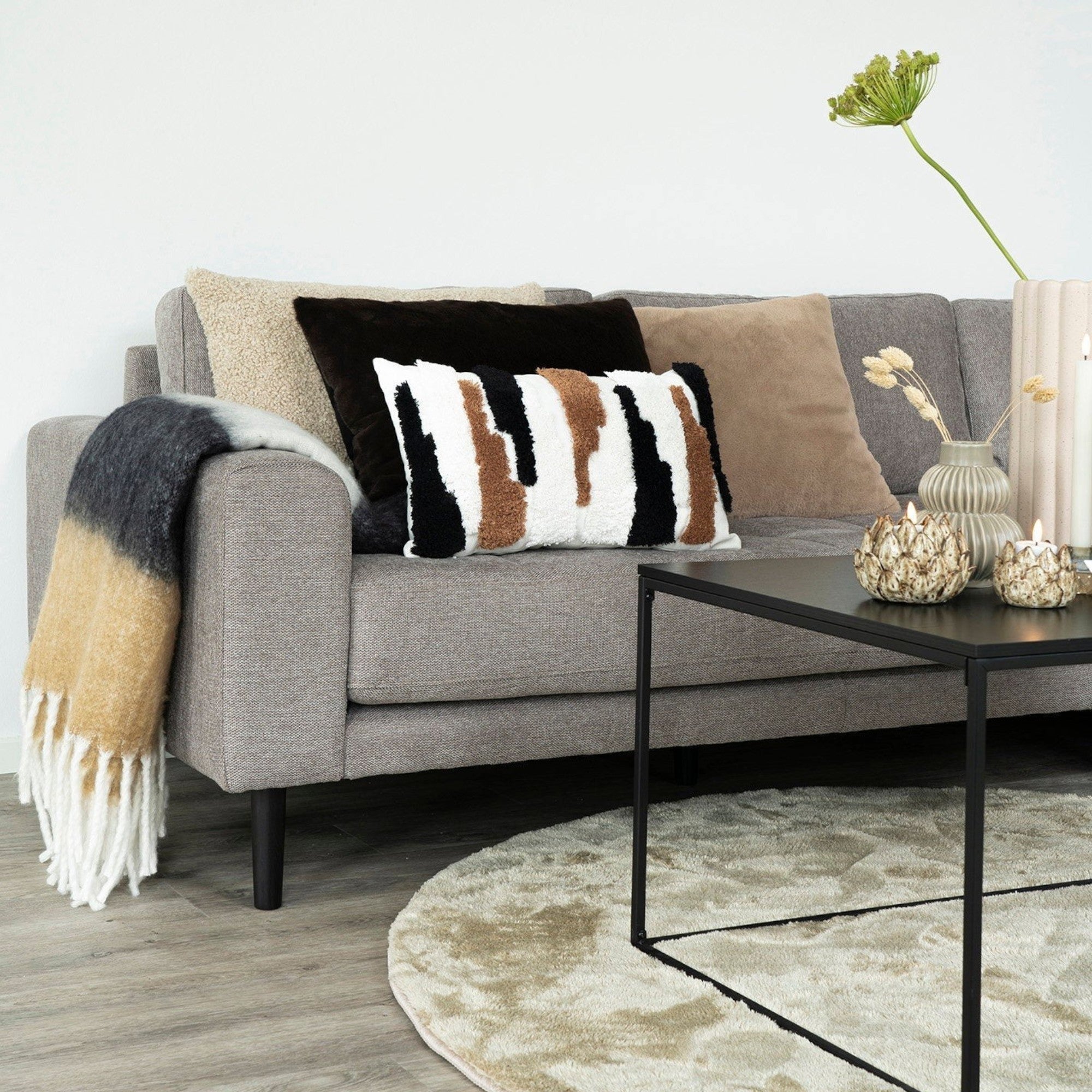 Kayu Living Sintra throw in black, white, and brown draped over a grey sofa with decorative pillows