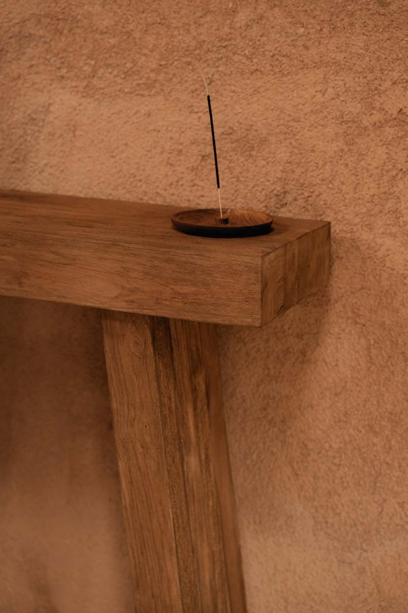 Kayu Living Stance Console table in natural Indonesian teak with visible wood grain against a textured wall.