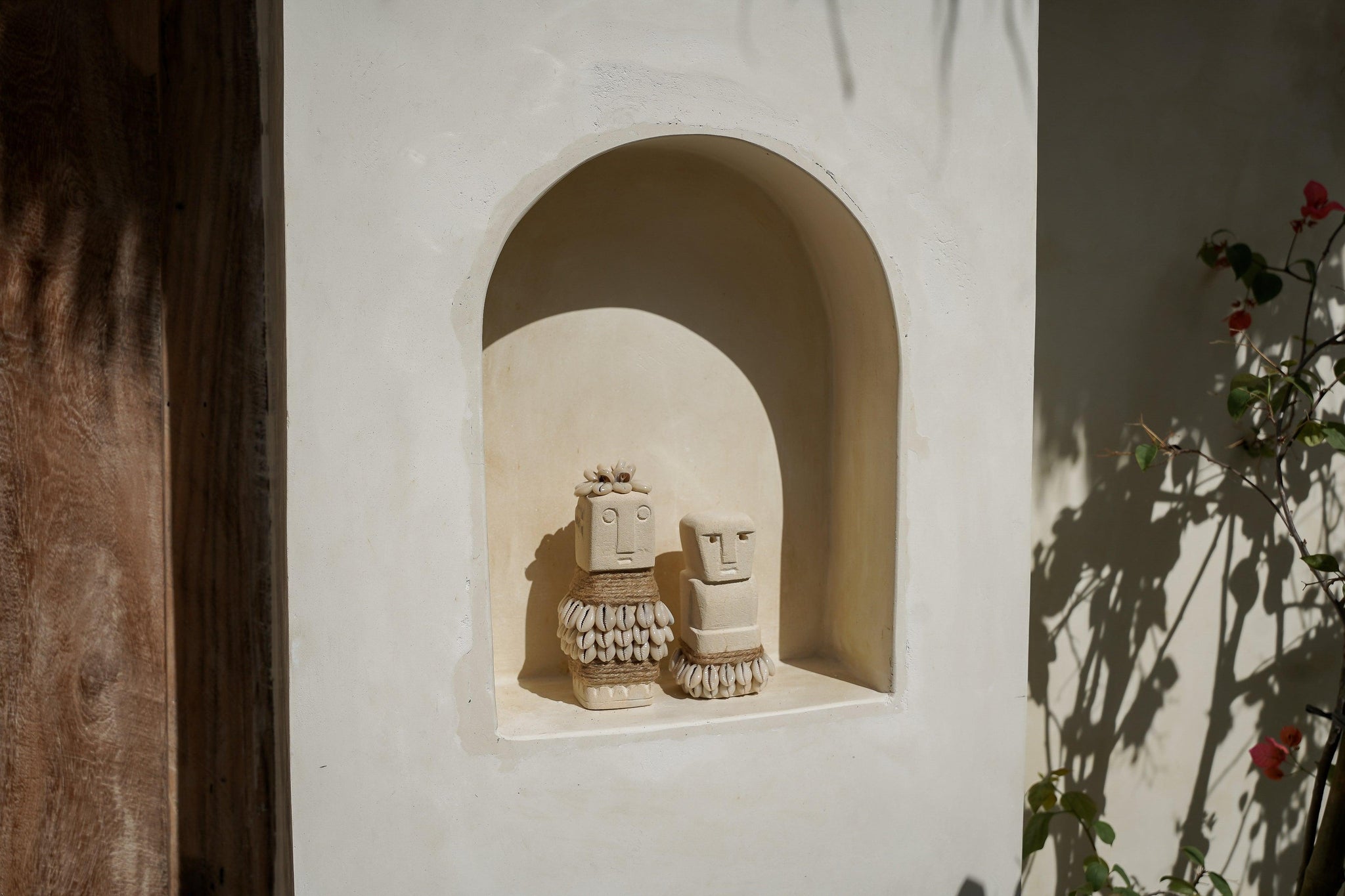 Kayu Living handmade natural stone figurines with shell and jute accents displayed in a white arched wall niche