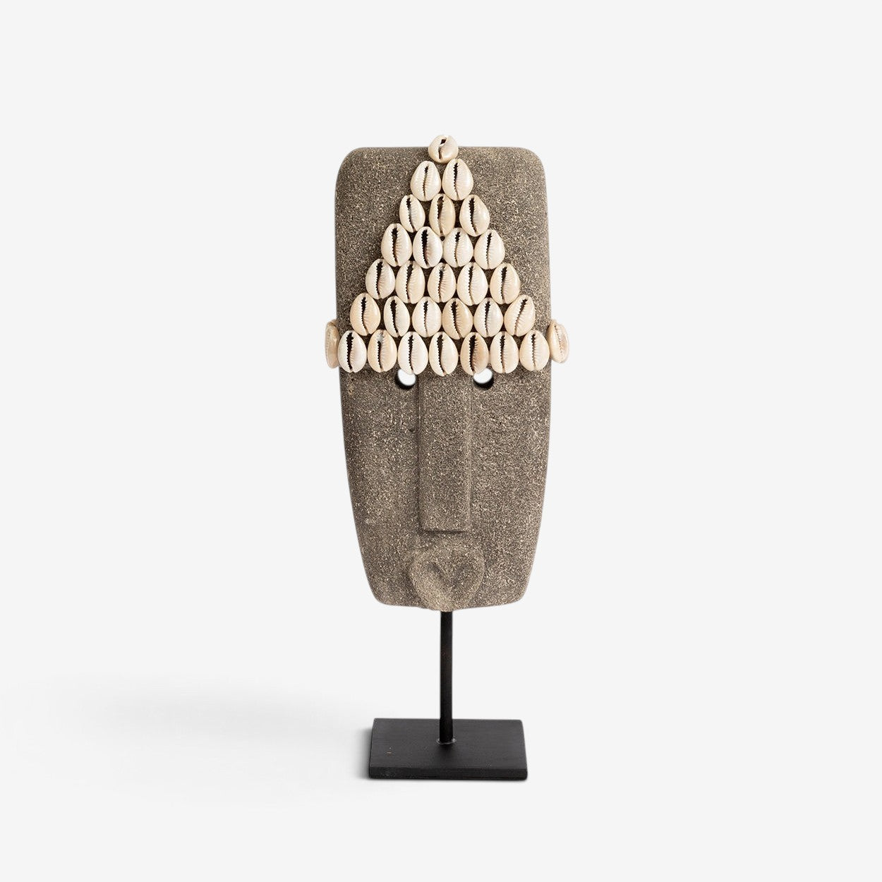 Kayu Living hand-carved grey sandstone Sumba stone statue decorated with cowrie shells on a black metal stand.