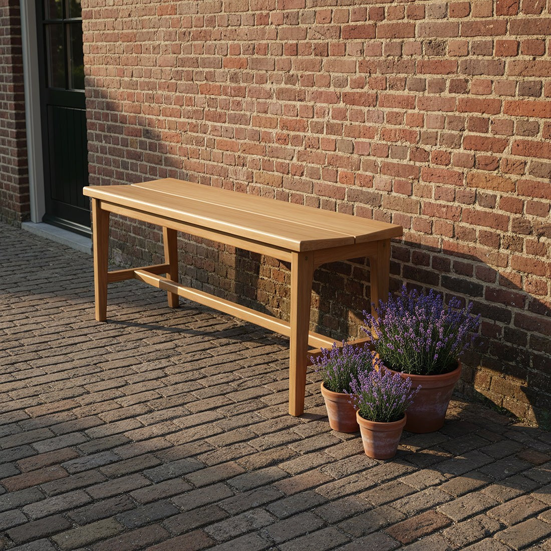 Kayu Living sustainable teak wood bench on a brick patio with potted lavender plants.