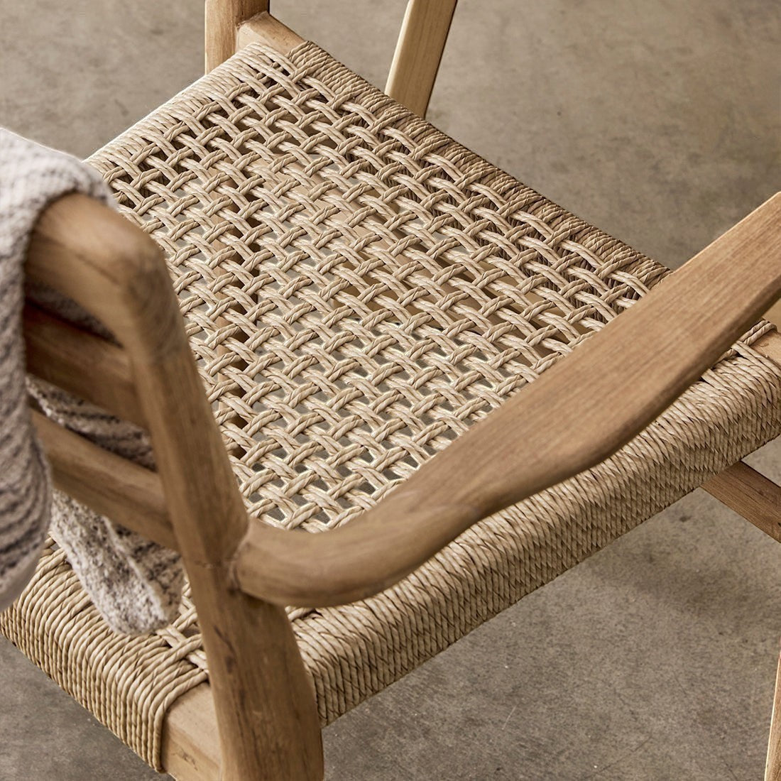 Kayu Living Verano teak garden chair with armrests featuring a woven rope seat and natural wood frame.