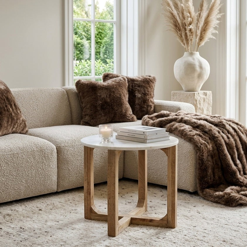 Kayu Living white marble side table with a solid mango wood cross-shaped base in a cozy living room setting.